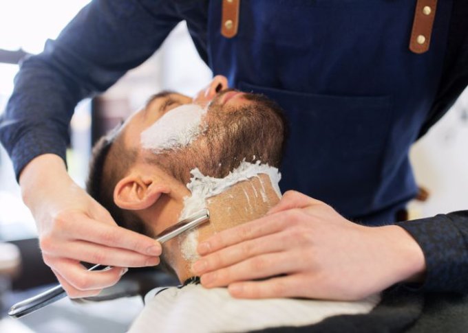 Fryzjer używa włoskich kosmetyków do golenia brody mężczyzny