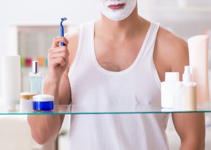 Mężczyzna goli się używając kosmetyków z zestawu
